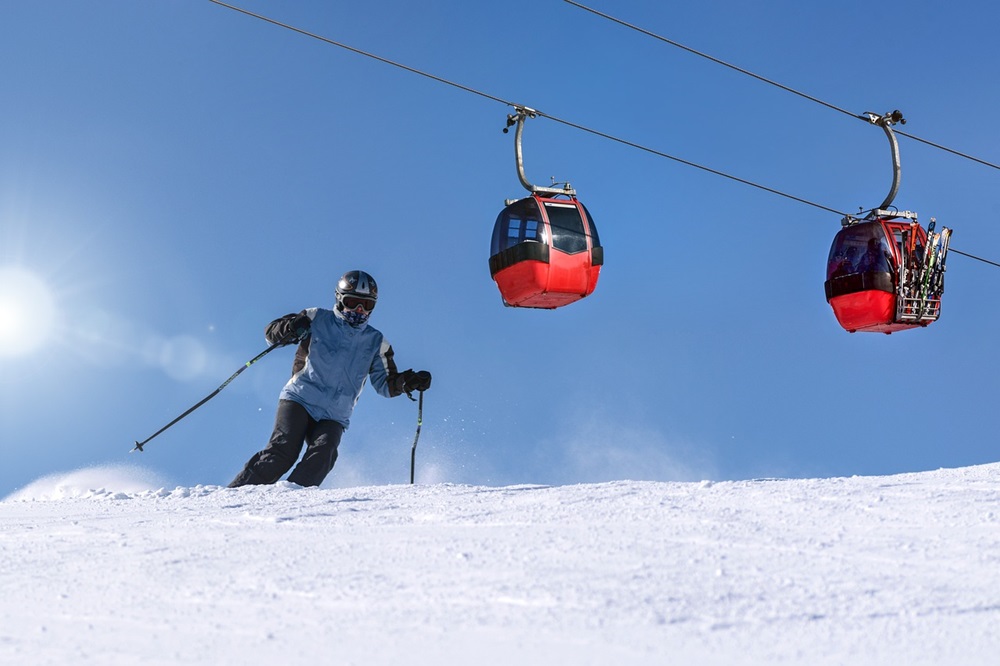 青空のもと、スキーをしている人とゴンドラ二台