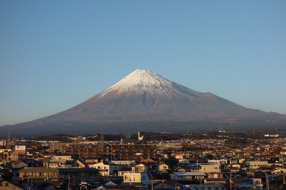 青空に富士山がそびえ、麓には町が広がっている