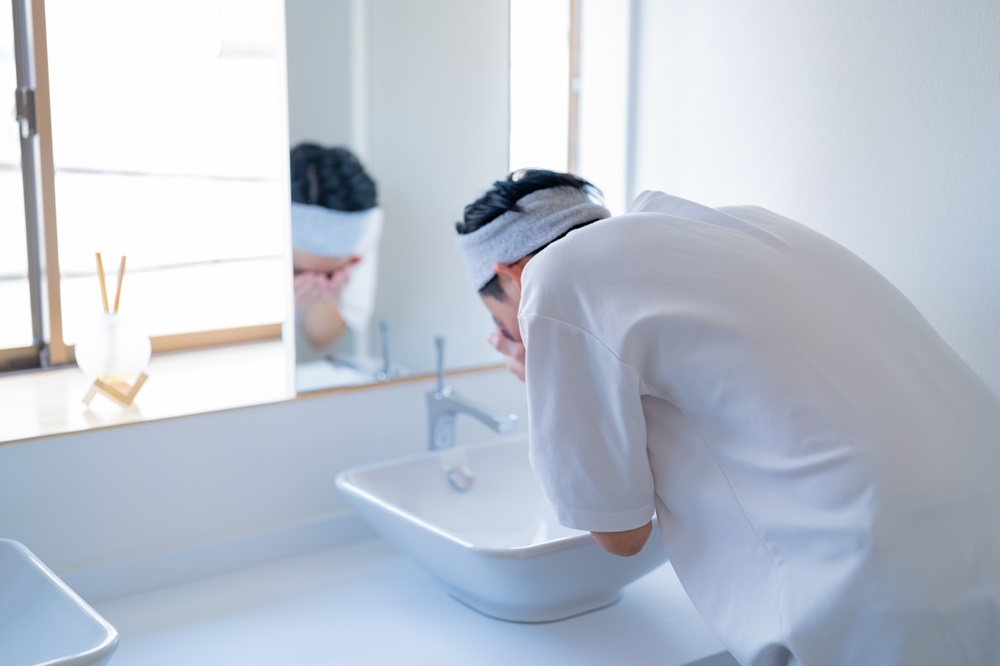 洗面台で男性が顔を洗っている